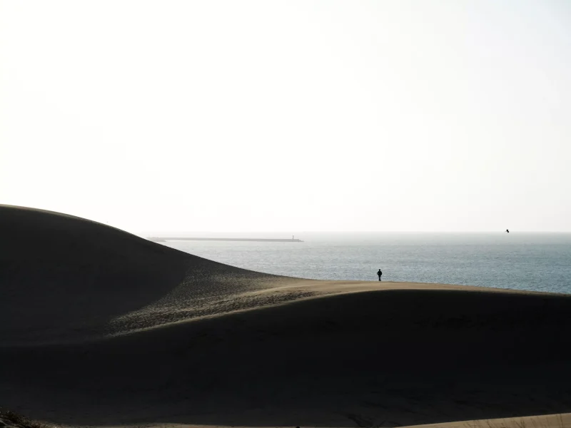 一位旅行者在沙漠上看著海景