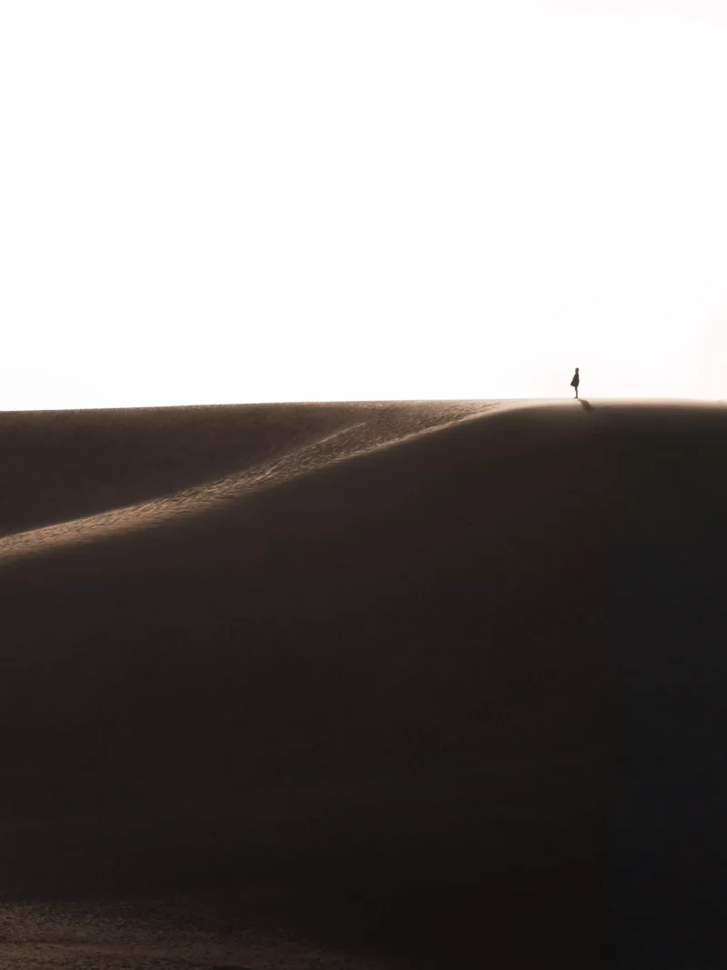 一名女人站在砂丘頂端眺望遠方