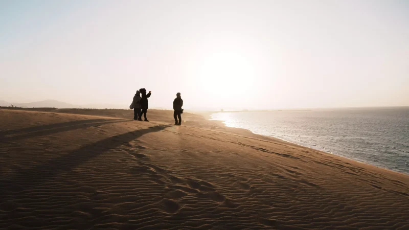 一群朋友在鳥取砂丘拍照的瞬間，正值傍晚風紋漸漸形成的時刻